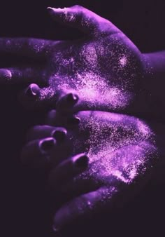 two hands covered in purple powder on top of each other