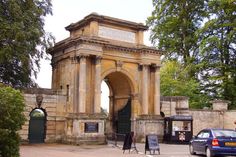 an old stone arch in the middle of a street with cars parked on the side