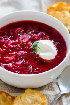 a white bowl filled with beet soup next to crackers