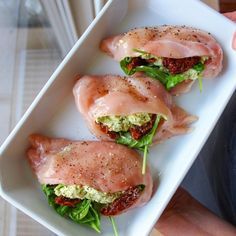 three pieces of chicken on top of lettuce and sauce in a white dish