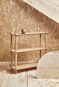 a wooden shelf sitting on top of a white floor next to a wall covered in wood