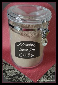 a glass jar filled with cocoa mix sitting on top of a red table cloth next to a black and white place mat