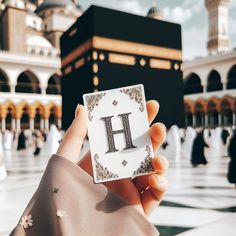 a person holding up a card with the letter h on it in front of a building