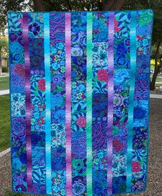 a blue and purple quilt hanging from a tree