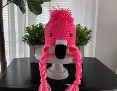 a pink crocheted hat with a white face and black nose is sitting on a table