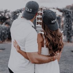 a man and woman embracing each other in front of a sign that says, dad