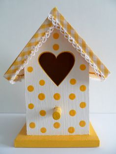 a white and yellow birdhouse with a heart on it