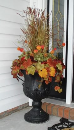 a black urn filled with lots of flowers on top of a door sill