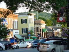 cars are parked on the street in front of buildings and trees with mountains in the background