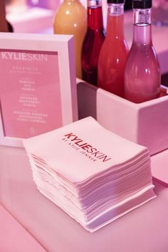 a stack of white napkins sitting on top of a table next to bottles of juice