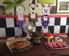 a table topped with lots of cakes and cupcakes next to a wall mural