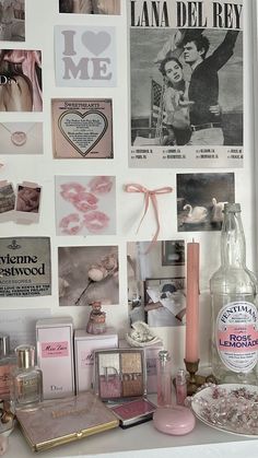 there are many pictures on the wall above the counter and in front of it is a bottle, candle, mirror, magnets