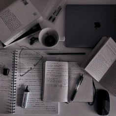 an apple laptop, notebook and pen on top of a desk with other office supplies