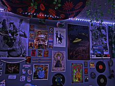 a wall covered in posters and pictures with lights on it's sides as well as decorations