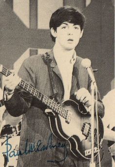 a man holding a guitar while standing in front of a microphone