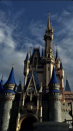 a large castle with many towers and blue domes on it's sides under a cloudy sky