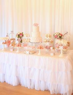 a table topped with lots of cakes and desserts on top of white cloth covered tables