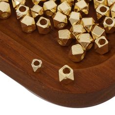 gold plated metal hexagonal beads are on a wooden stand with wood grain