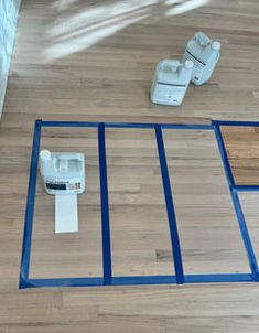 the floor is being laid out with blue tape on it and two pieces of wood are laying next to each other