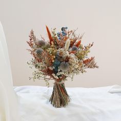 a vase filled with lots of flowers sitting on top of a white table covered in cloth