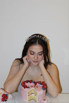 a woman sitting at a table with a cake in front of her