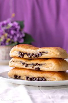 three chocolate chip scones on a white plate with purple flowers in the back ground