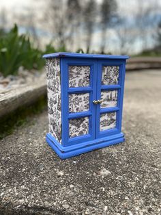 a small blue phone booth sitting on the ground