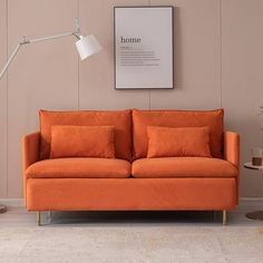 an orange couch sitting in front of a lamp