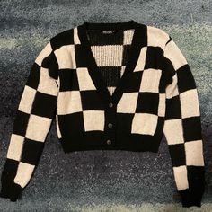 a black and white checkered cardigan sweater laying on the ground