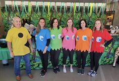 a group of people standing next to each other in front of a wall with plants on it