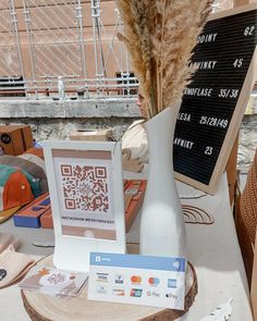 a white vase sitting on top of a wooden table next to a sign that says qr code