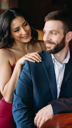 a man and woman sitting next to each other in front of a wooden counter top