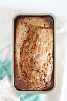 a loaf of banana bread sitting in a pan on top of a white table cloth