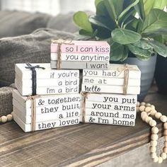 four wooden blocks with words on them sitting on a table next to a potted plant