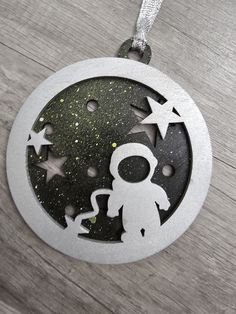 a metal ornament with an astronaut and stars in the center on a wooden surface