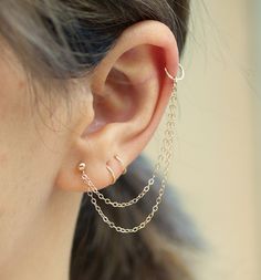 a close up of a person's ear with two chains attached to the ear