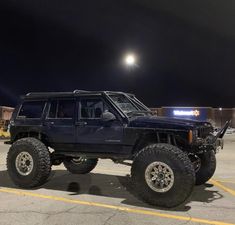 a blue jeep parked in a parking lot at night