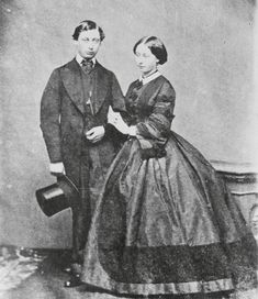 an old black and white photo of a man and woman in formal dress standing next to each other