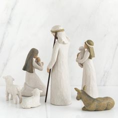 three ceramic figurines of people and animals on a white surface with marble background