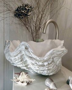 a white bowl sitting on top of a counter next to seashells and branches