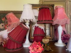 three lamps are sitting on a table next to a mirror and vase with flowers in it