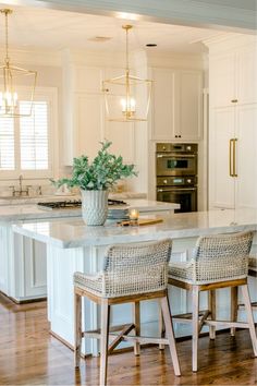 a large kitchen with white cabinets and an island in the middle is decorated with wicker bar stools