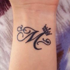 a small wrist tattoo with the letter m on it's left arm and crown in the middle