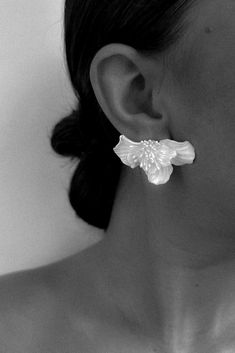 black and white photograph of a woman wearing large earrings with flowers on the back of her ear