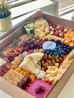 a box filled with lots of different types of cheeses and crackers next to a potted plant