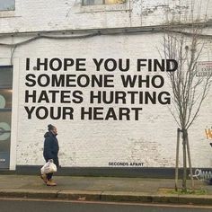 a man walking down the street in front of a white building with graffiti on it