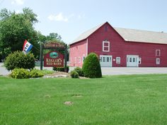 a large red barn with a flag on it's roof and a sign for the king's bed inn