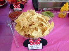 a bowl filled with tortilla chips on top of a pink tablecloth covered table