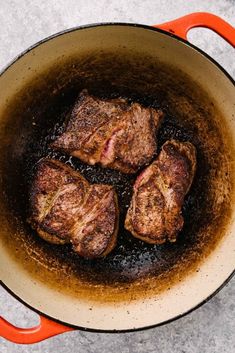 three steaks are cooking in a skillet on the stove top, with brown liquid