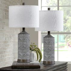 two lamps sitting on top of a table next to a vase with flowers in it